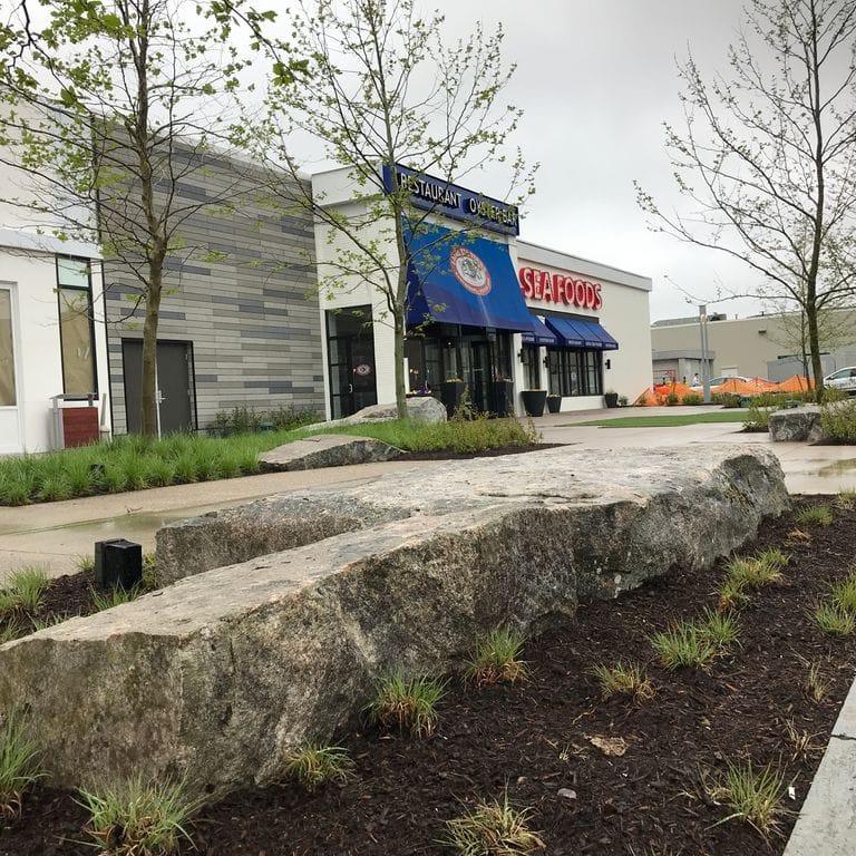 Application image for New England Fieldstone Boulders &amp; Ledgestone - Seating &amp; Benches. The image shows this product being used for seating &amp; benches and landscape boulders &amp; ledge. The surface finish shown is weathered. The dominant color shown is gray. The color mix creates a warm feeling.