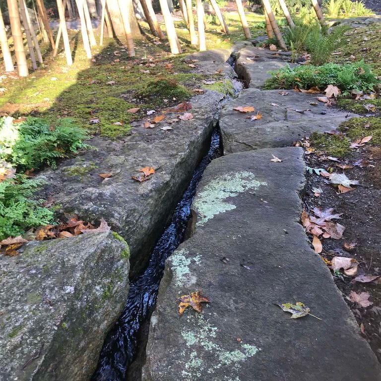 Application image for New England Fieldstone Boulders &amp; Ledgestone - Pool/Pond Coping. The image shows this product being used for water features and landscape boulders &amp; ledge. The surface finish shown is weathered. The dominant color shown is gray. The color mix creates a warm feeling.