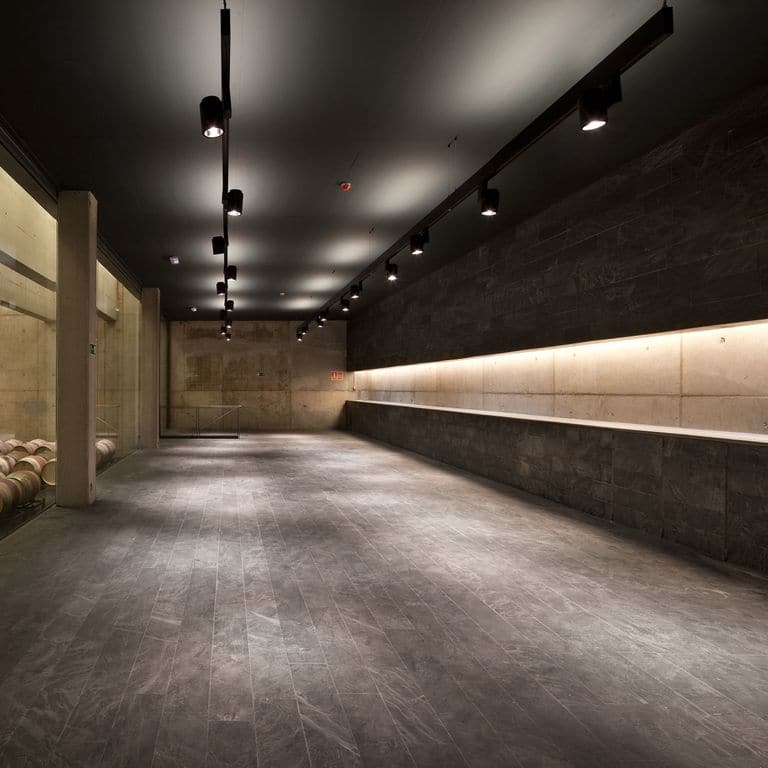 Application image for Slate - Iberian Gray - Pavers. The image shows this product being used in an interior floor application. The surface finish shown is flamed. Dominant colors shown are black and gray. Linear color pattern.