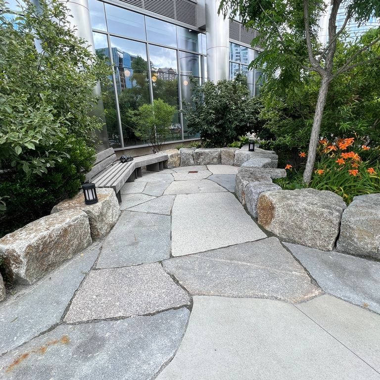 Feature image for Granite - Reclaimed Block - Seating Walls. The image shows this product being used for seating &amp; benches and landscape curbing &amp; edging. The dominant color shown is gray. The color mix creates a warm feeling.