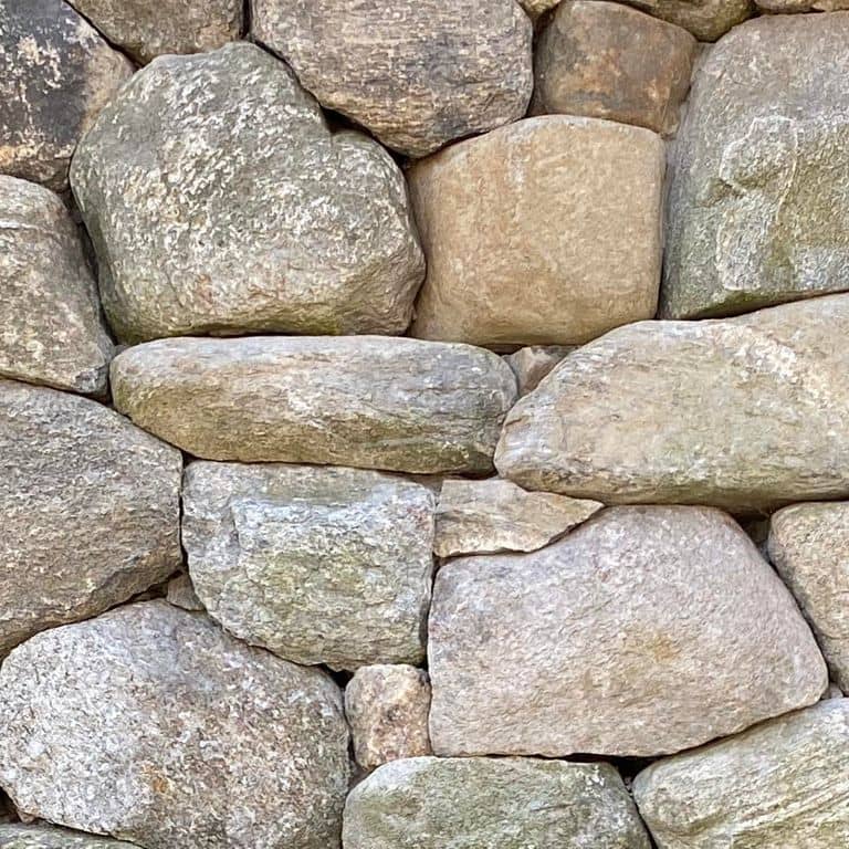 Best close-up image for New England Fieldstone Mix - Veneer. The image shows this product being used for full bed veneer and thin veneer. The surface finish shown is weathered. Dominant colors shown are beige, gray and tan; with brown, green, orange/rust, pink, purple, white and cream secondaries. Exhibits "movement" and the color mix creates a warm feeling. Streaked, speckled and cloudy color patterns.