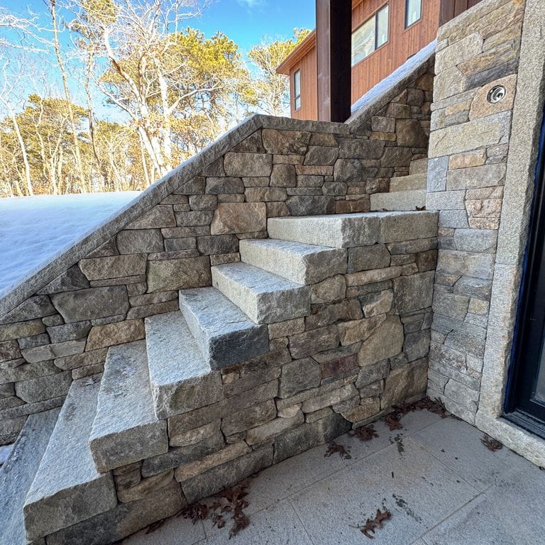 Application image for New England Fieldstone Mix - Veneer. The image shows this product being used in a full bed veneer application. The surface finish shown is weathered. The dominant color shown is gray.