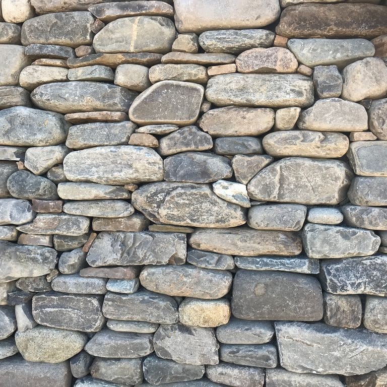 Best close-up image for New England Fieldstone Flats - Veneer. The image shows this product being used for full bed veneer and thin veneer. The surface finish shown is weathered. Dominant colors shown are beige, gray and tan; with brown, green, orange/rust, pink, purple, white and cream secondaries. Exhibits "movement" and the color mix creates a warm feeling. Streaked, speckled and cloudy color patterns.