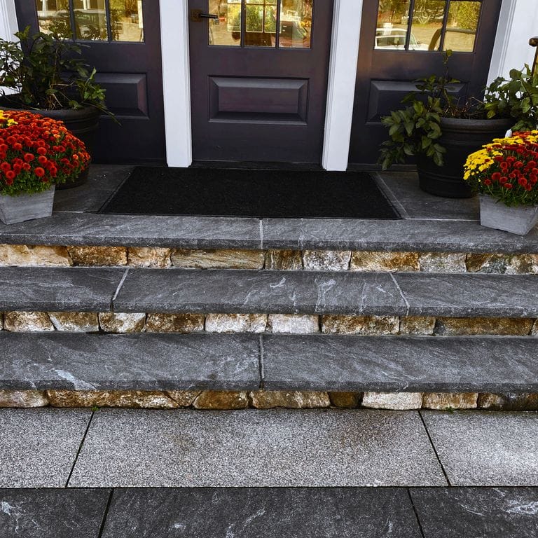 Application image for Granite - Jet Mist - Steps and Treads. The image shows this product being used in a treads application. Dominant colors shown are black and gray; with a white secondary. Exhibits "movement" and the color mix creates a cool feeling. Fine speckled and cloudy color patterns.