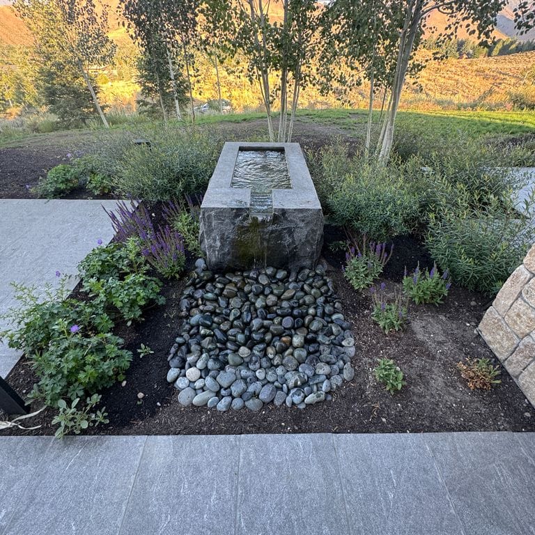 Application image for Granite - Jet Mist - Water Feature. The image shows this product being used for water features, garden accents and sculpture &amp; carvings. The surface finish shown is split-face. The dominant color shown is gray. The color mix creates a warm feeling.