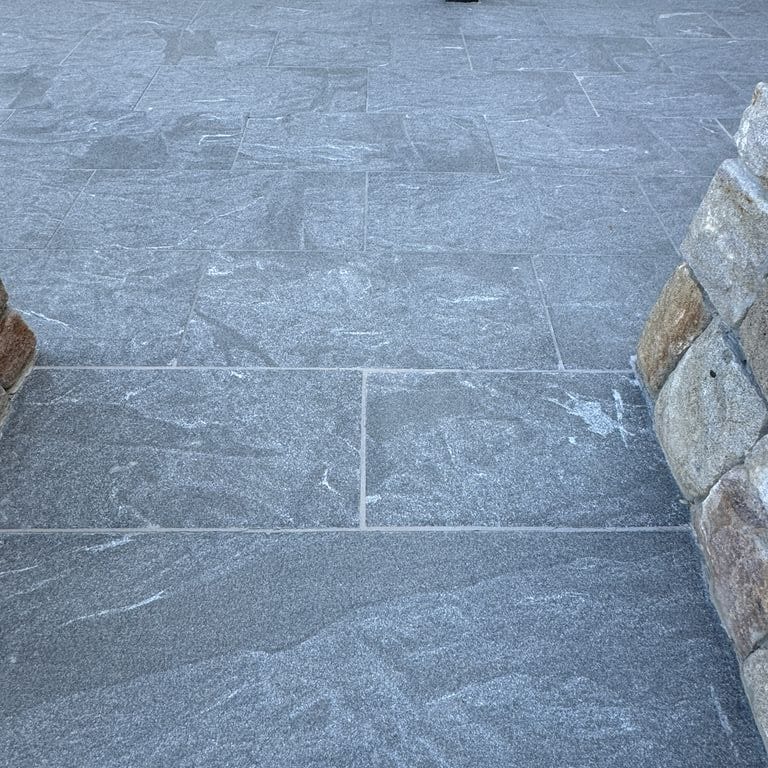 Application image for Granite - Jet Mist - Pavers. The image shows this product being used in a patio pavers application. The dominant color shown is gray. The color mix creates a cool feeling.
