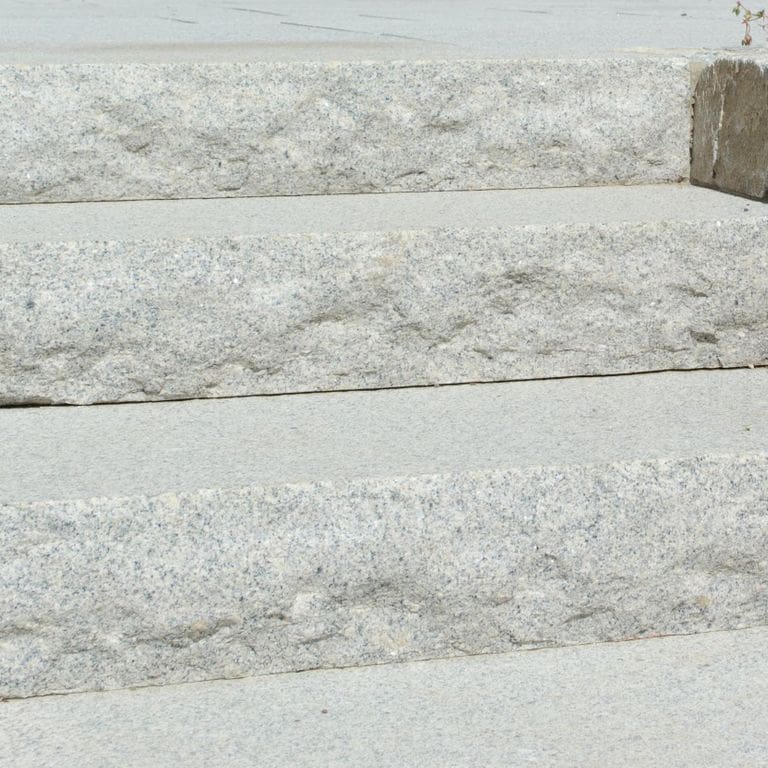 Close-up image for Cape Neddick Granite Clear - Rockfaced Steps. The surface finishes shown are flamed and rockfaced. Dominant colors shown are gray and white; with beige, pink and cream secondaries. Speckled and fine speckled color patterns.
