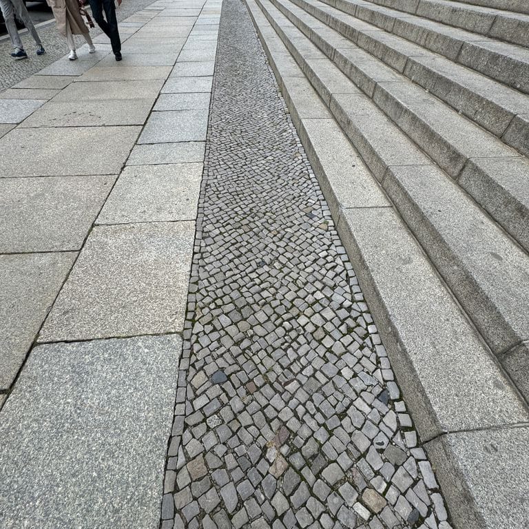 Application image for Granite - Reclaimed Berlin Sidewalk Stones. The image shows this product being used in a path pavers application. The surface finish shown is . The dominant color shown is gray. The color mix creates a cool feeling.