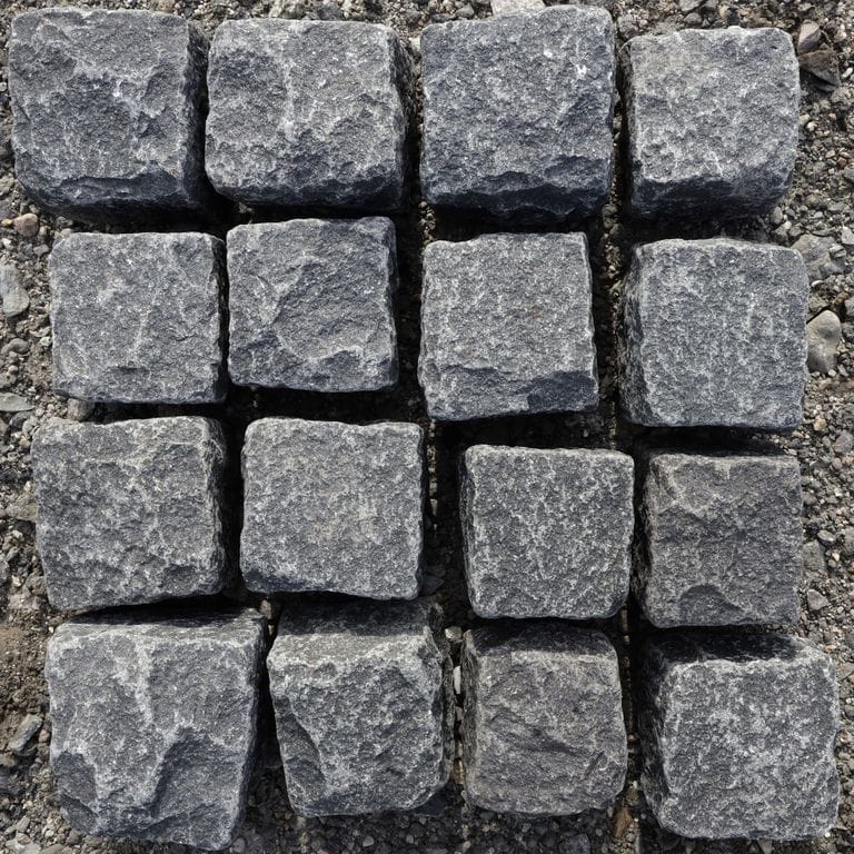 Feature image for Black Granite Cobblestones - Squares. The dominant color shown is gray. Exhibits "movement" and the color mix creates a cool feeling. Swirled and speckled color patterns. Contains some mica.