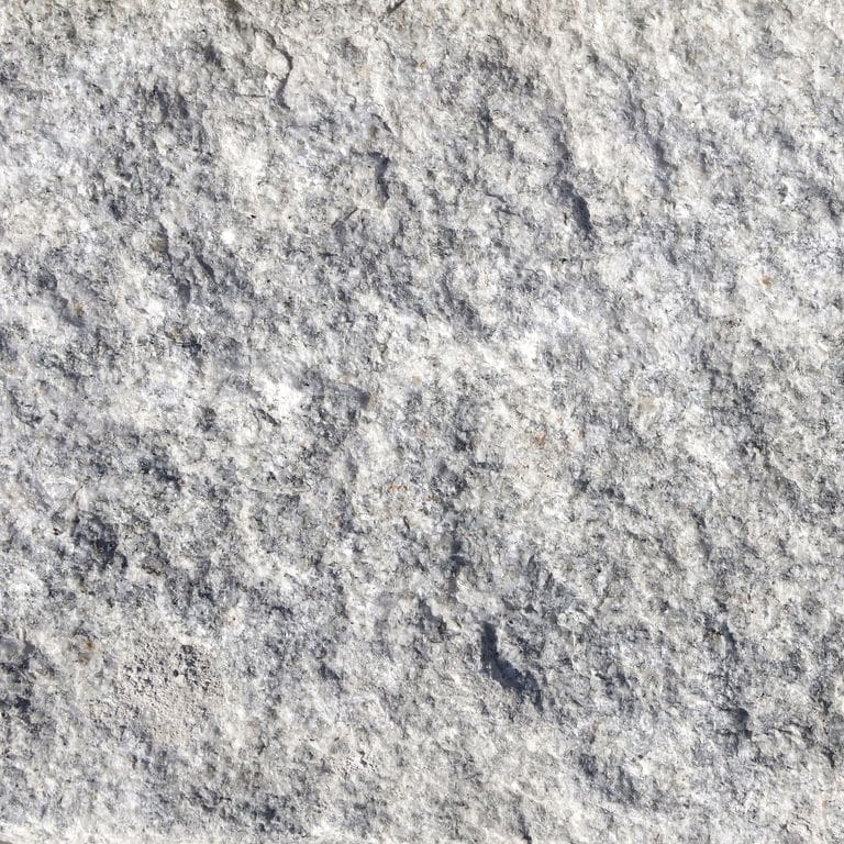 Swatch image cropped for Gray Granite Cobblestone - Squares. The surface finishes shown are split-face, split-face with flat plane and tumbled. The dominant color shown is gray; with beige, white and cream secondaries. Exhibits "movement" and the color mix creates a cool feeling. Regular, speckled and swirled color patterns. Contains some mica.