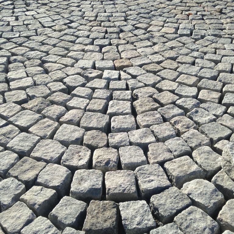 Application image for Gray Granite Cobblestone - Squares. The image shows this product being used in a patio pavers application. The surface finish shown is . The dominant color shown is gray. The color mix creates a cool feeling.