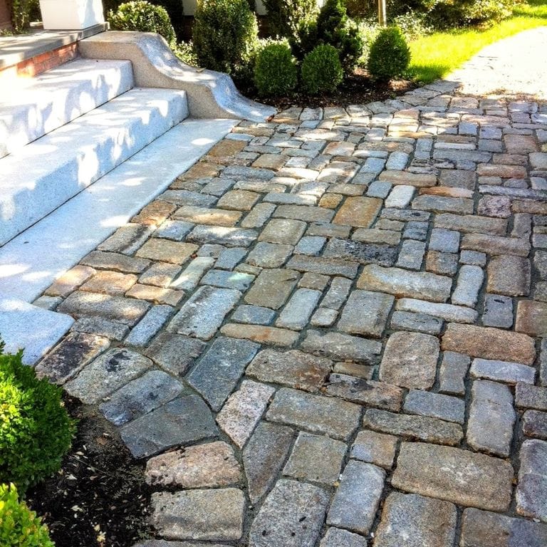 Feature image for Reclaimed New England Cobblestones - Jumbo Wide Side. The image shows this product being used in a path pavers application. The surface finish shown is . The dominant color shown is gray. The color mix creates a warm feeling.