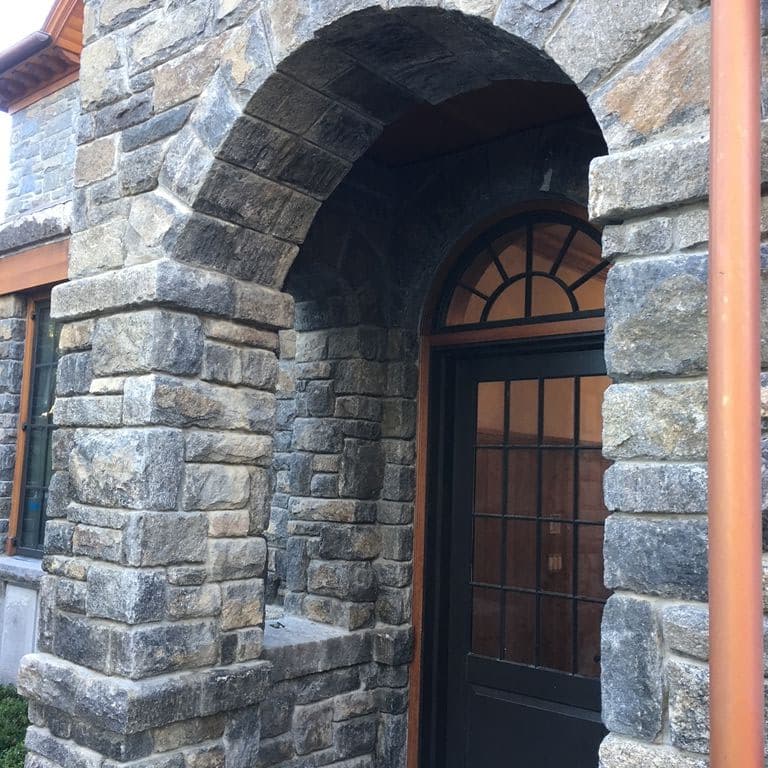Application image for New England Fieldstone - Barre Dark Veneer. The image shows this product being used for full bed veneer and thin veneer. The surface finish shown is weathered. Dominant colors shown are gray and tan. The color mix creates a cool feeling.