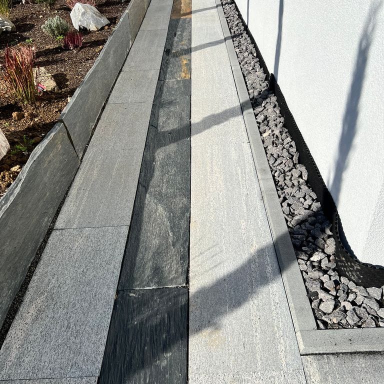 Application image for Brazilian Lucerna Gneiss - Flamed Pavers. The image shows this product being used in a path pavers application. The surface finish shown is flamed. The dominant color shown is gray. The color mix creates a warm feeling.