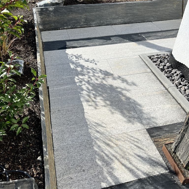 Application image for Brazilian Lucerna Gneiss - Flamed Pavers. The image shows this product being used in a path pavers application. The surface finish shown is flamed. The dominant color shown is gray. The color mix creates a warm feeling.