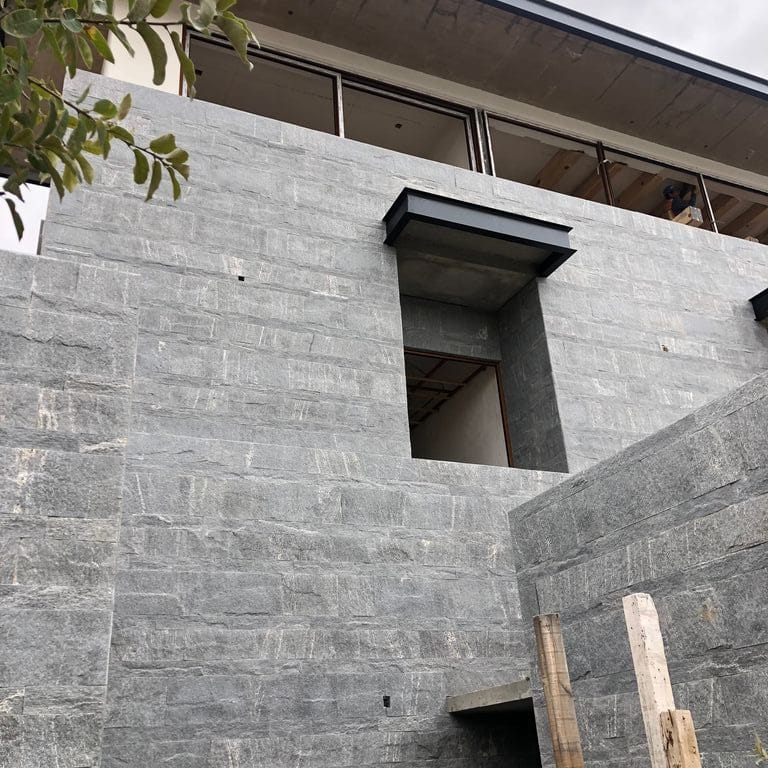 Application image for Brazilian Lucerna Gneiss - Veneer. The image shows this product being used in a full bed veneer application. The surface finish shown is split-face. The dominant color shown is gray. The color mix creates a cool feeling.