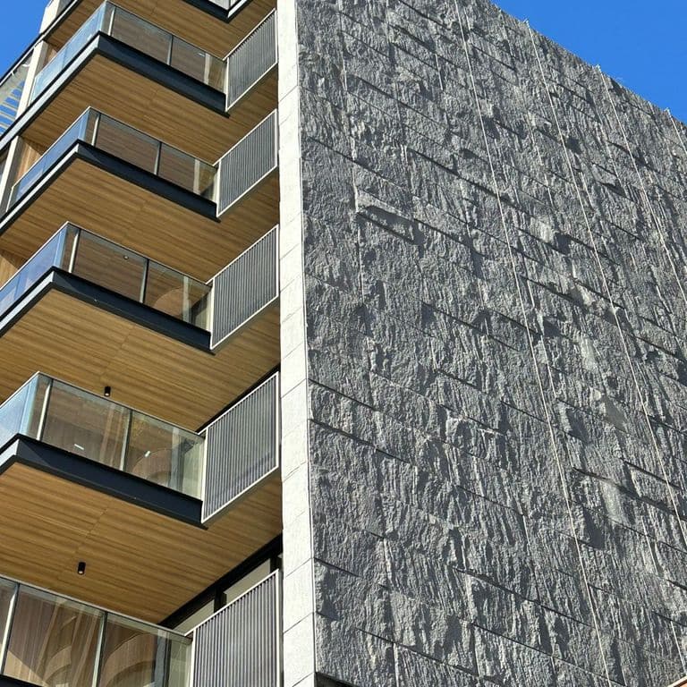Application image for Brazilian Lucerna Gneiss - Veneer. The image shows this product being used in a full bed veneer application. The surface finish shown is split-face. The dominant color shown is gray.