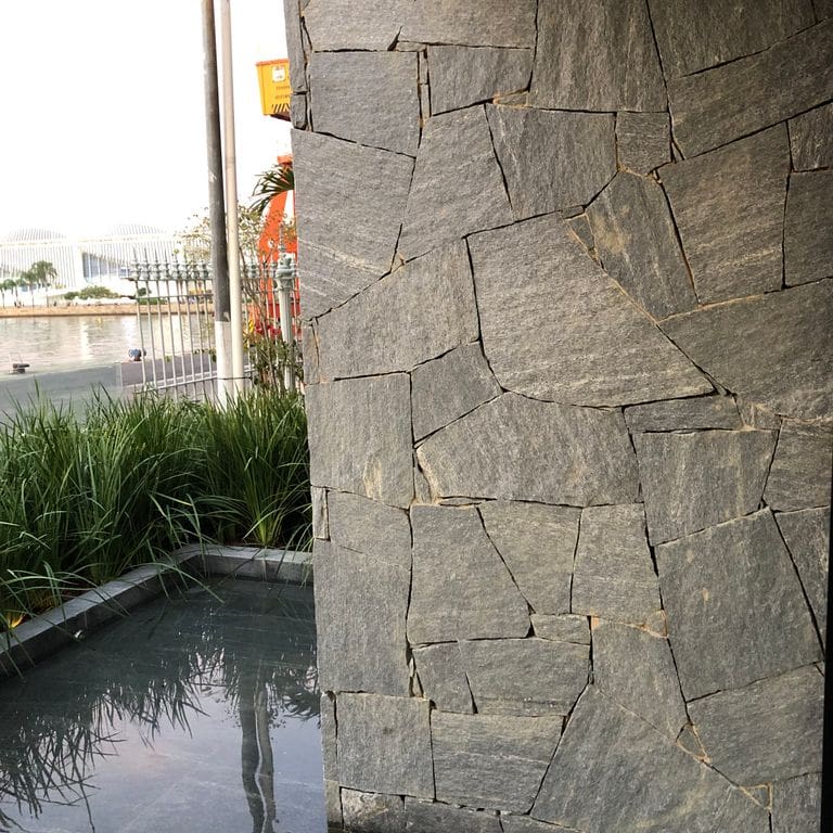 Application image for Brazilian Lucerna Gneiss - Veneer. The image shows this product being used in a full bed veneer application. The surface finish shown is split-face. The dominant color shown is gray. The color mix creates a warm feeling.