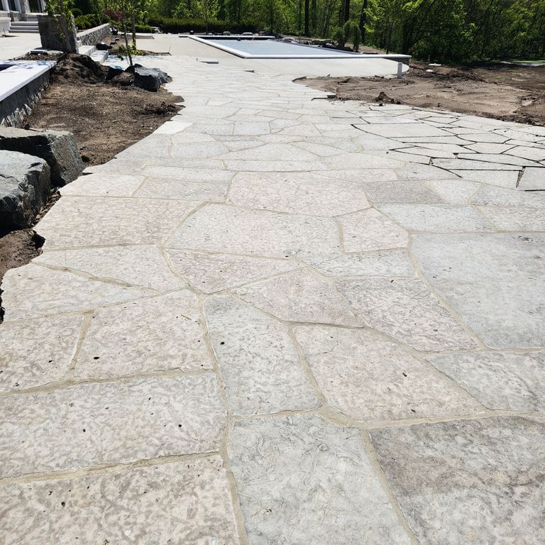 Application image for Madison Limestone - Irregular Pavers. The image shows this product being used for patio pavers and pool deck pavers. The surface finish shown is flamed. The dominant color shown is gray. The color mix creates a cool feeling.