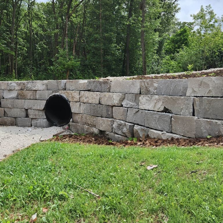 Feature image for Lannon Gray Limestone - Wallstone. The image shows this product being used for landscape wallstone and retaining wall. The surface finish shown is natural cleft. The dominant color shown is gray. The color mix creates a warm feeling.